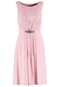 Robe rose pâle sans manches avec des plis verticaux sur le corsage, ornée de bijoux à la taille et une jupe fluide.