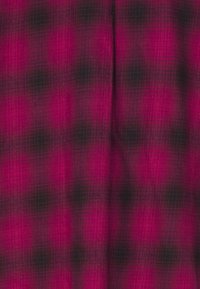 Rutigt tyg i nyanser av magenta och svart, med en mjuk textur och ett rutmönster med suddiga kanter. Lämpligt för olika textilapplikationer.