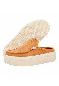 Tan suede slip-on shoes with a textured upper and a thick cream-colored rubber sole featuring a chevron pattern.