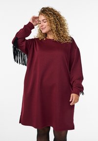 Abito sovradimensionato bordeaux con maniche lunghe, con accenti di frange nere sui polsini e un collo rotondo. Tessuto morbido con una vestibilità rilassata.