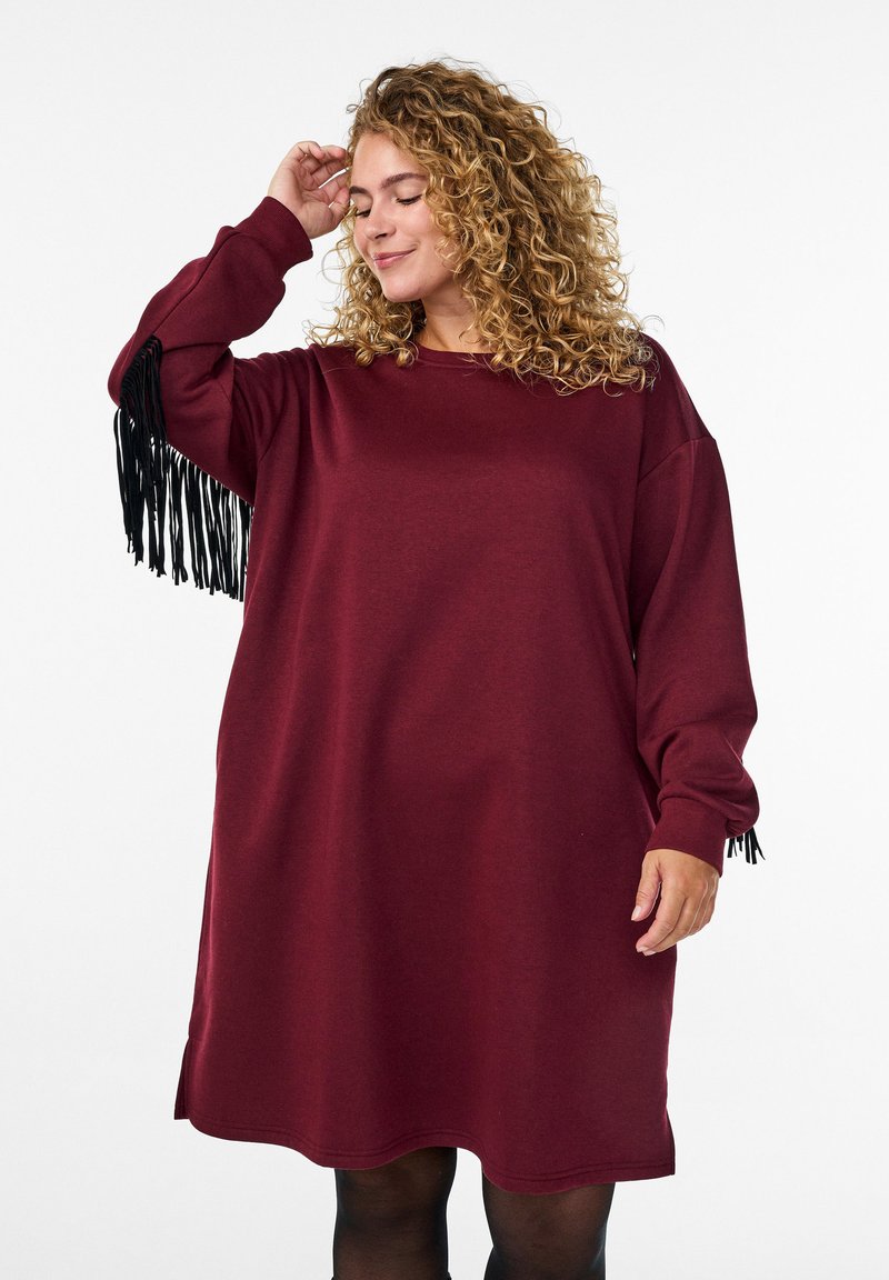 Abito sovradimensionato bordeaux con maniche lunghe, con accenti di frange nere sui polsini e un collo rotondo. Tessuto morbido con una vestibilità rilassata.