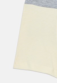 Chemise en coton à manches courtes avec un haut gris et un bas à rayures jaunes. La section jaune présente de fines rayures blanches et une texture lisse.