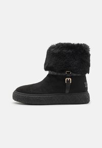 Czarne botki na kostkę wykonane z zamszu, z mankietem z sztucznego futra, ozdobione dekoracyjnym paskiem z klamrą w złotym odcieniu oraz teksturowaną gumową podeszwą.