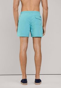 Shorts da bagno azzurri con una texture liscia, cintura elastica e una tasca posteriore con pattina. Adatti per attività acquatiche.