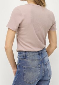 Jasnoróżowa bluzka z krótkim rękawem, ribbed, z okrągłym dekoltem, połączona z dżinsami w kolorze niebieskim o wysokim stanie z tylnymi kieszeniami.