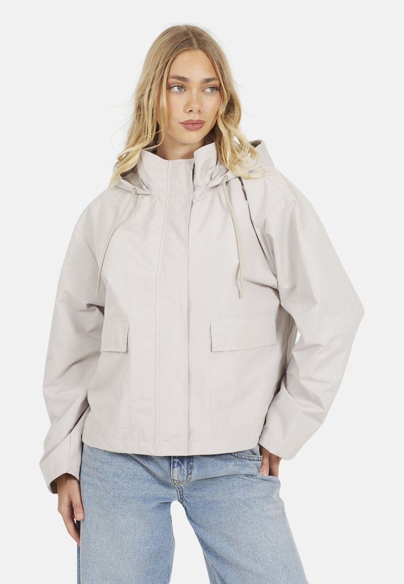 Veste capuche beige clair avec une coupe décontractée. Dotée de deux poches avant et d'accents à cordon. Fabriquée à partir d'un matériau lisse et résistant à l'eau.