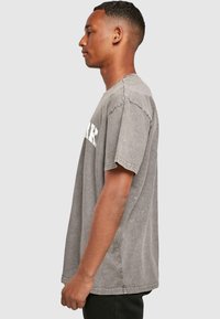 Grijze katoenen T-shirt met korte mouwen, met een relaxte pasvorm en zichtbare stiksels. "PARK" in dikke witte letters gedrukt op de voorkant.