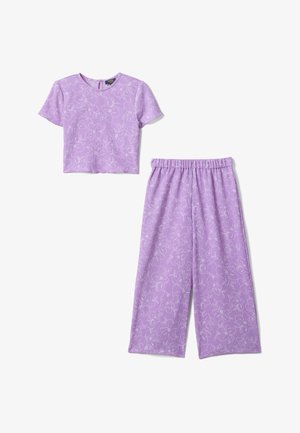 Haut court lilas à manches courtes et pantalon large assorti avec imprimé floral blanc et ceinture élastique, disposés à plat sur fond blanc.
