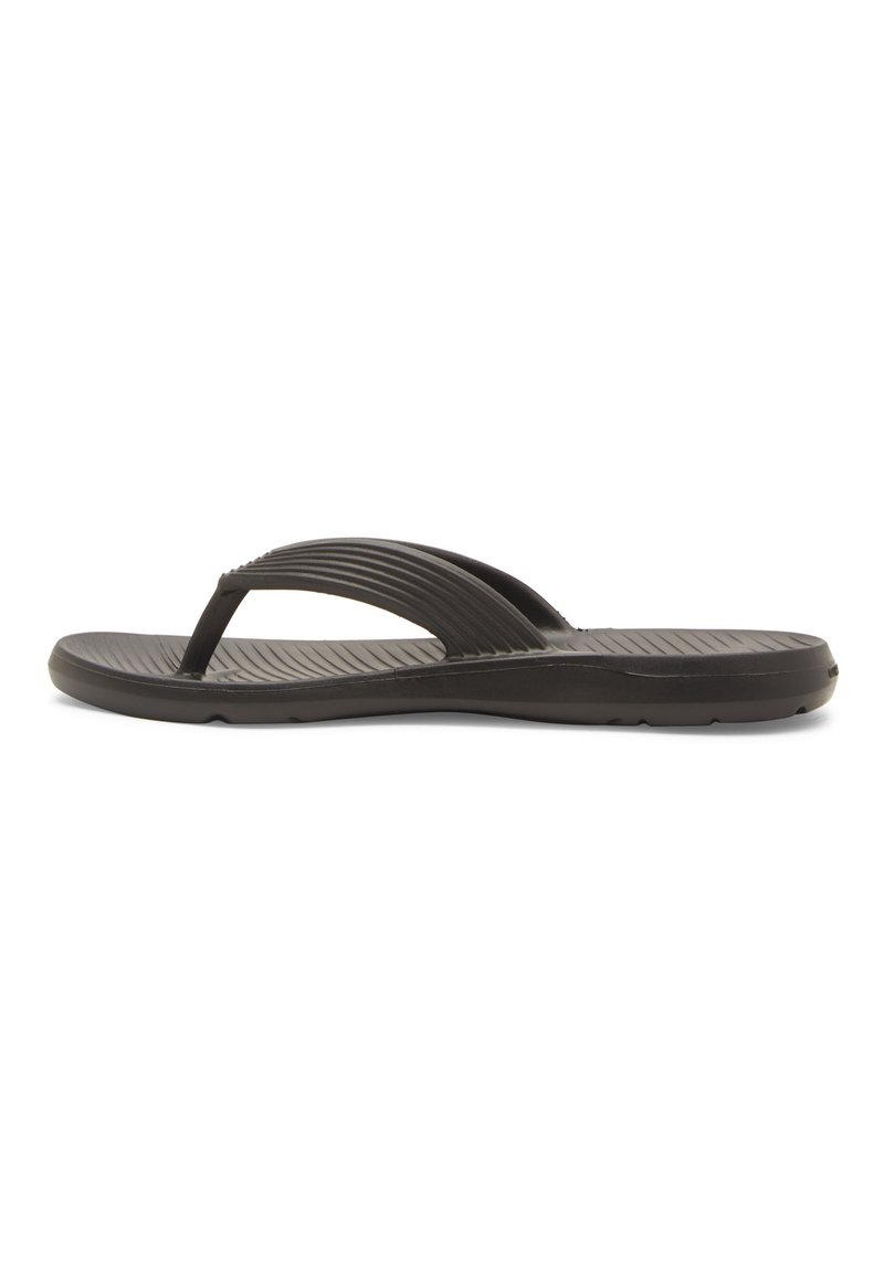 Sandale noire en tongs en caoutchouc, avec une sangle supérieure texturée dotée de rainures horizontales et une semelle plate et rembourrée.