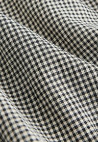 Black and cream checkered fabric with a textured weave, featuring small squares in a consistent pattern, suitable for various textile applications.
