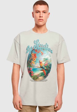 Lys grå oversized t-shirt med et farverigt tropisk grafik med blomster og en papegøje i et cirkulært design. Blød bomuldsstruktur.
