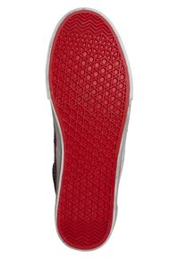 Semelle de chaussure rouge en caoutchouc avec un motif de semelle en losanges et hexagones, des bords blancs et une finition texturée pour une meilleure adhérence et durabilité.