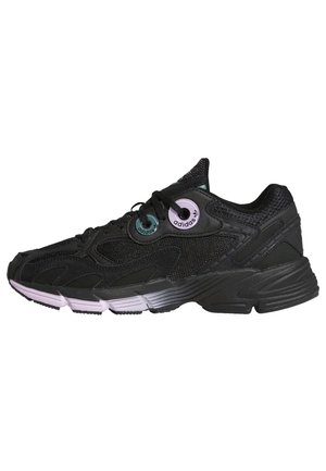 Scarpa sportiva nera con tomaia in rete e dettagli viola. Presenta una suola spessa e un design strutturato, adatta per sport o uso quotidiano.