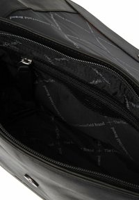 Interno di una borsa in pelle nera con un comparto con zip, caratterizzato da una fodera in tessuto nero con marchio, con testo ripetuto e una texture liscia.