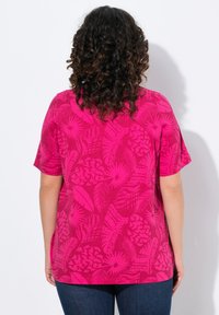 Kortärmad, livfullt rosa t-shirt med ett stort blad- och blommönster. Mjuk textur, något lös passform och rund halsringning.