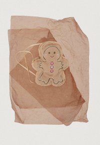 Vankúšik v tvare perníka s usmievavou tvárou a ružovými gombíkmi, odpočívajúci na vrstvených hnedých pokrčených papierových hárkoch.