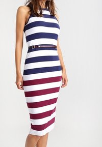 Randig midiklänning i vitt med marinblå och vinröda horisontella ränder, som har en figursydd design och ett tunt brunt bälte i midjan.