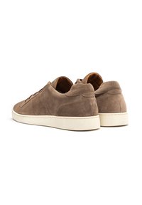 Brązowe zamszowe sneakersy o niskim profilu, z białą gumową podeszwą, sznurowanym zapięciem i kontrastującym beżowym wnętrzem.