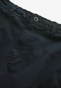 Svarta tygshorts med en jämn textur, med knappstängning och sydda detaljer längs midjebandet och fickorna.