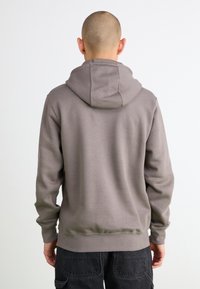 Lysegrå hoodie med afslappet pasform, justerbar hætte og ribbede manchetter. Glat tekstur og minimal syning, med en kengurulomme.