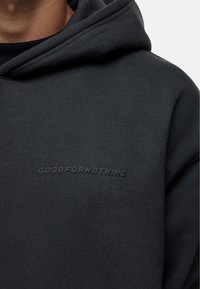 Felpa nera con cappuccio realizzata in tessuto morbido, con vestibilità rilassata e logo "GOODFORNOTHING" embossato sul petto. Design semplice e privo di decorazioni.