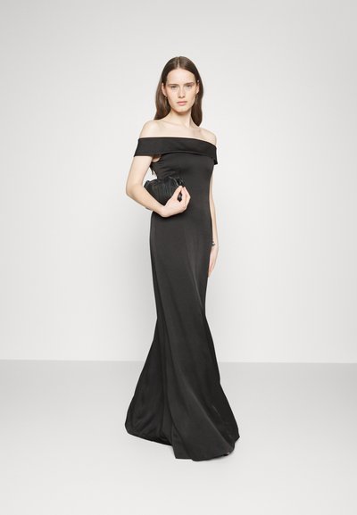 Abito lungo da sera nero, con spalle scoperte e design aderente, caratterizzato da una texture liscia e una silhouette fluida, abbinato a una piccola pochette a righe.