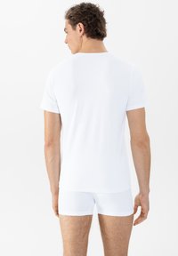 Witte katoenen t-shirt met korte mouwen, ronde halslijn en witte boxershorts. Minimalistisch ontwerp, gladde textuur en aangesloten pasvorm.