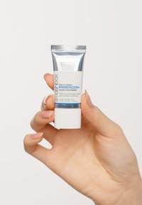 Le Smashbox Photo Finish Primerizer dans un tube argenté et blanc. L'étiquette présente un texte bleu et un capuchon blanc mat. Taille de 10 mL.