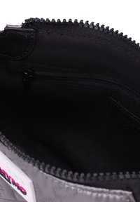 Interno trapuntato grigio di una borsa con una cerniera nera, una piccola tasca con zip e una fodera in tessuto liscio.