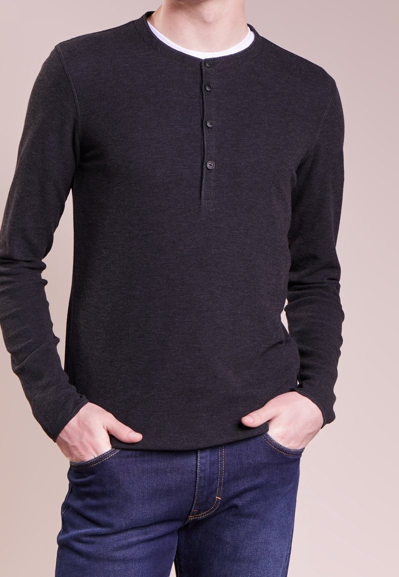 Mörkgrå långärmad henley-tröja av ribbat tyg; har en rund halsringning och en tre-knappars knappslå på framsidan.