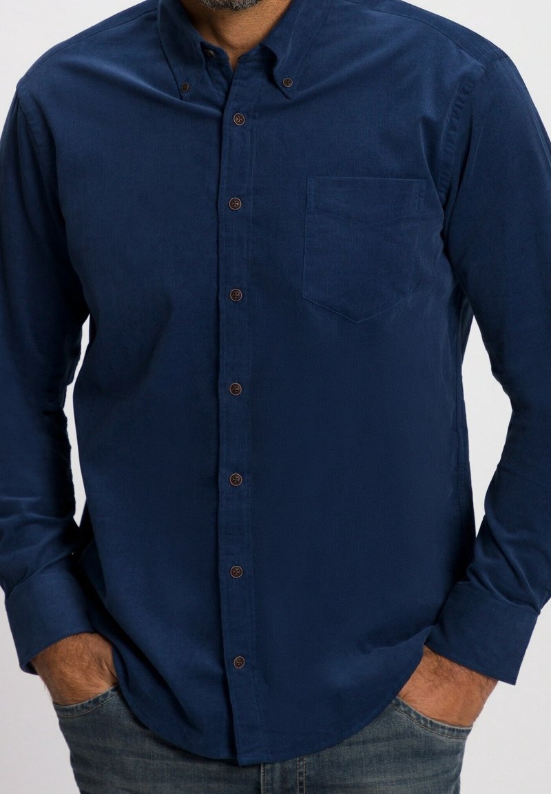 Marinblå knäpp skjorta, tillverkad av slät tyg, med en bröstficka, bruna knappar och långa ärmar. Avslappnad passform med rundad nederkant.
