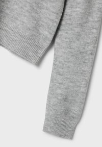Manche de pull en tricot gris avec un poignet côtelé. Texture douce, motif légèrement chiné et forme effilée visibles.