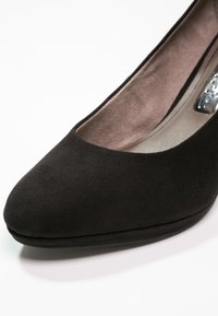 Black suede women's high heel shoe with rounded toe and beige cushioned insole on a white background.