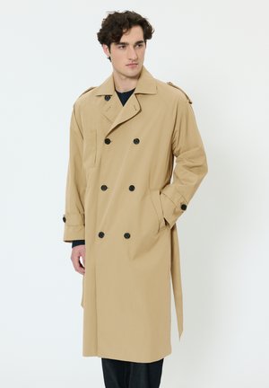 Beige trenchcoat med dobbeltradet front, sorte knapper, sidelommer og bælte i taljen. Glat stof med skræddersyet pasform.