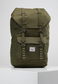 Oliwkowy plecak z materiału z designem typu roll-top, dwoma regulowanymi paskami, przednią kieszenią na klapę oraz naszywką z logo. Teksturowany materiał.