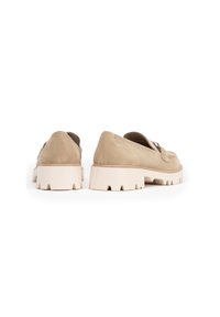 Zapatos de ante beige con una suela blanca gruesa, que cuentan con una puntera redondeada, detalle de hardware decorativo y una textura suave.