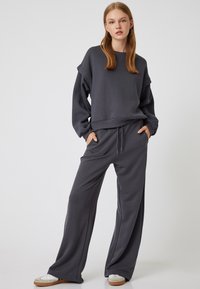 Sudadera gris y pantalones anchos a juego, hechos de una tela suave. La sudadera tiene un corte holgado, con puños y un escote de cuello redondo.