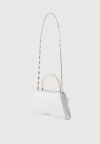 Λευκή τσάντα σε σχήμα τραπεζοειδούς με χερούλι στην κορυφή διακοσμημένο με μαργαριτάρια και ασημένια αλυσίδα λουράκι, μινιμαλιστικός σχεδιασμός, λογότυπο Steve Madden στο μπροστινό μέρος.