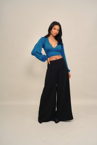 Tengeri kék rövid felső puffos ujjakkal és mély V-nyakkivágással, fekete, bőszárú nadrággal párosítva. Sima, enyhén fényes anyag.