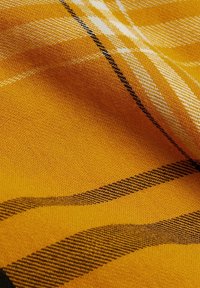 Tissu jaune présentant un motif à carreaux tissé, avec des rayures noires et blanches, affichant une texture douce et une teinte chaude et vibrante.