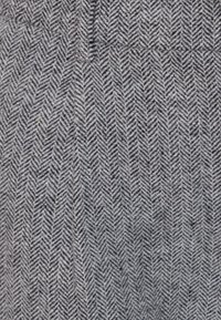 Ulltyg med fiskbensmönster i nyanser av grått, med små chevronmotiv och en mjuk, strukturerad yta.