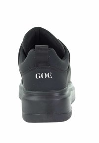 Czarny sneaker z teksturowaną cholewką, gumową podeszwą i pętlą do zakupu. Na pięcie znajduje się białe logo "GOE". Gładki i minimalistyczny design.