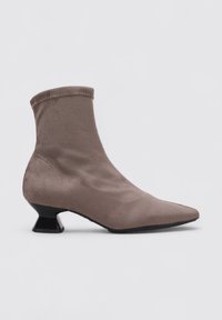 Bottine en suède gris avec un bout pointu, une tige courte et un talon géométrique noir unique. Texture lisse avec des détails de couture visibles.