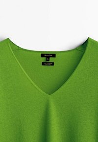 Pull vert en laine cachemire à col en V avec col visible et étiquette de marque noire "Massimo Dutti" à l'intérieur du col.