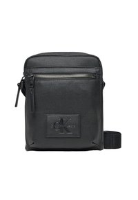 Bolso cruzado negro hecho de material texturizado. Presenta un zipper en la parte superior y un bolsillo frontal, logo embossado y correa ajustable.