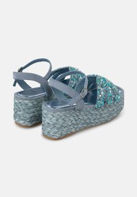 Sandali in suede blu con cinturini decorati, dotati di un tacco a zeppa spesso intrecciato in azzurro e una soletta argentata lucida.