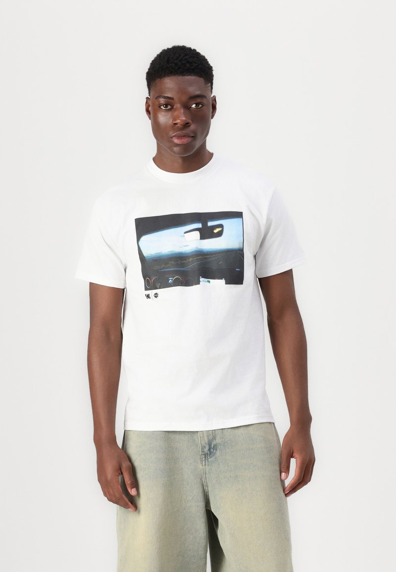 White cotton t-shirt featuring a printed graphic of a car's interior view with blue and black tones. Short sleeves and a relaxed fit.