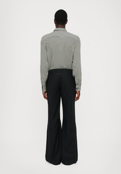 Chemise à manches longues à carreaux noir et blanc avec col, associée à un pantalon noir taille haute évasé. Texture lisse, coupe ajustée.