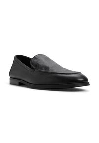 Zwarte leren loafers met een gestructureerd oppervlak, instapontwerp en een lage profielzool. Gladde accenten langs de stiksels.