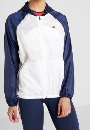 Leichter, kapuzen Windbreaker in Weiß und Marineblau, mit einem Reißverschluss vorne, elastischen Bündchen und einem kleinen Logo auf der Brust.